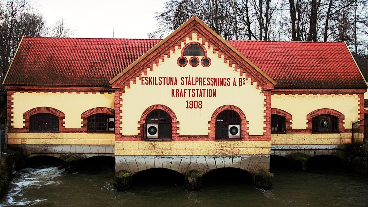 A building with a red roof sitting next to a river
